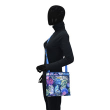 Load image into Gallery viewer, Mannequin wearing black clothing and carrying an Anuschka Fabric with Leather Trim Crossbody with Slip Pocket - 12017 shoulder bag with an adjustable handle.
