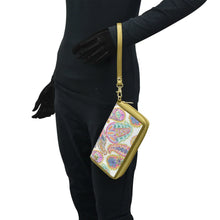 Load image into Gallery viewer, Person in a black outfit carrying an Anuschka RFID protected, patterned Fabric with Leather Trim Wristlet Travel Wallet - 13000 with zip entry.
