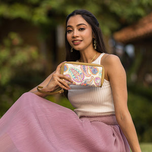 A woman in a pink skirt holding an Anuschka Fabric with Leather Trim Wristlet Travel Wallet - 13000 outdoors.