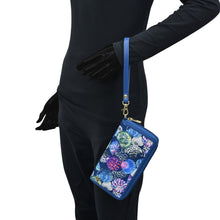 Load image into Gallery viewer, Person in a black bodysuit holding an Anuschka Fabric with Leather Trim Wristlet Travel Wallet - 13000 with a blue strap, featuring RFID protected card holders.
