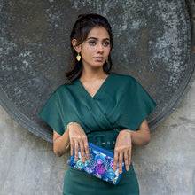 Load image into Gallery viewer, Woman in emerald dress holding a Anuschka Fabric with Leather Trim Wristlet Travel Wallet - 13000 with an RFID protected card holder.
