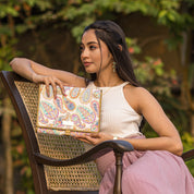 A woman posing with an Anuschka Fabric with Leather Trim Toiletry Case - 13001 featuring zippered pockets while sitting on a chair outdoors.