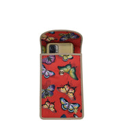 Anuschka Fabric with Leather Trim Cell Phone Crossbody Wallet - 13005 with a camera visible, tucked into a red case with a colorful butterfly pattern and a magnetic flap.