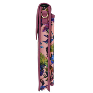 A rolled-up Anuschka yoga mat with a crossbody strap, featuring a tropical floral pattern.
