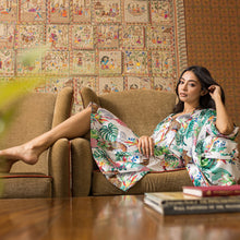 Load image into Gallery viewer, Woman relaxing in a Anuschka silk robe on a sofa with patterned cushions in a room with decorative wall art.

