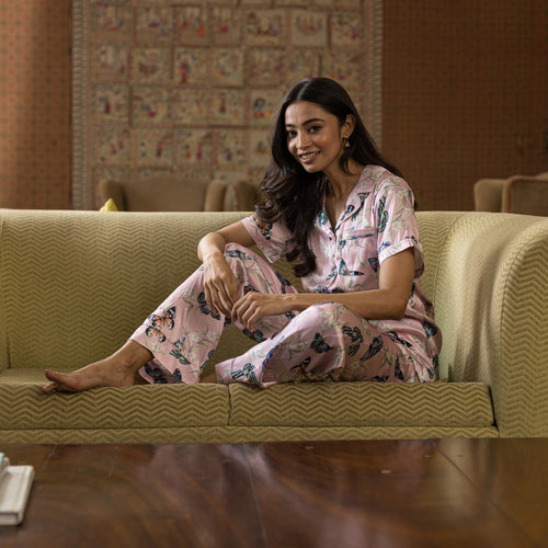 Woman in classic floral Anuschka pajama set - 3344 made of recycled fabric, sitting on a couch with a content expression.