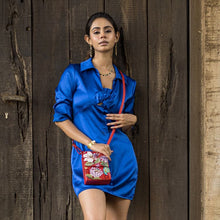 Load image into Gallery viewer, Woman in a blue dress posing with an Anuschka Triple Compartment Crossbody Organizer - 412 handbag against a wooden backdrop.
