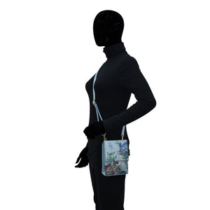 Profile of a mannequin dressed in a black outfit with gloves, wearing an Anuschka Triple Compartment Crossbody Organizer - 412 with a floral design.