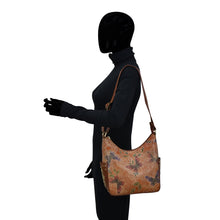 Load image into Gallery viewer, A mannequin wearing a black turtleneck and gloves, with a floral-patterned, genuine leather Anuschka Classic Hobo With Studded Side Pockets - 433 shoulder bag.
