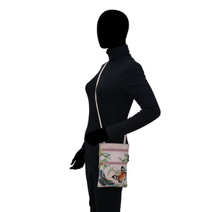 Mannequin displaying a black outfit and a Anuschka Mini Double Zip Travel Crossbody - 448 with hand-painted artwork.