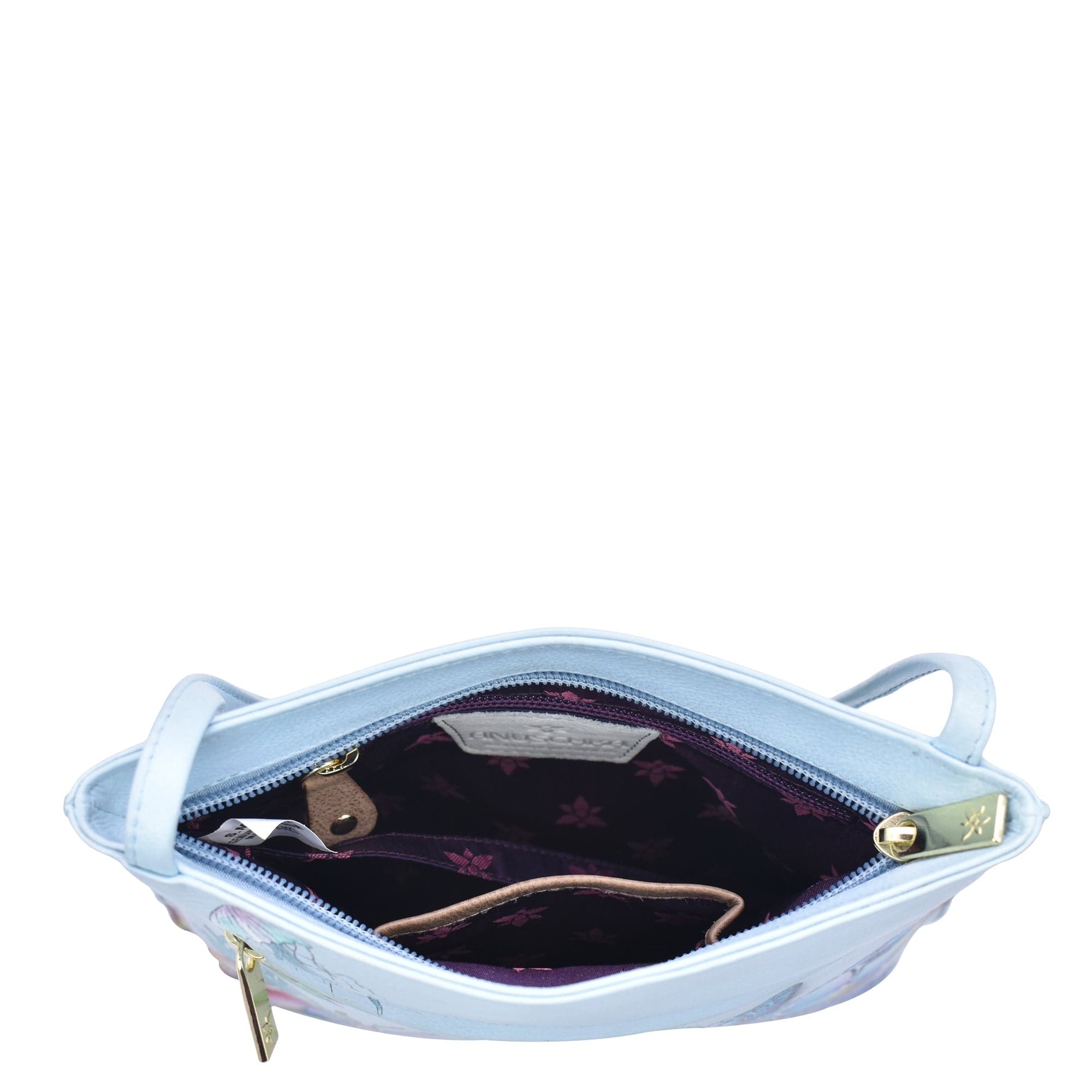 Light blue Anuschka Slim Crossbody With Front Zip - 452 with a floral-patterned interior, partially open, showing contents inside against a white background.
