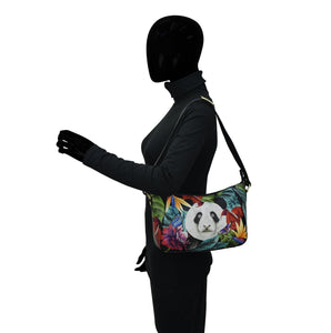 A person with a black mannequin head wearing a turtleneck and carrying an Anuschka Everyday Shoulder Hobo - 670 with a panda design over the shoulder.