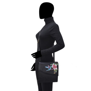 Mannequin displaying a black outfit with a Anuschka Flap Messenger Crossbody - 692 purse with floral leather.