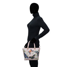 Load image into Gallery viewer, A mannequin wearing a black turtleneck and holding an Anuschka Medium Tote - 693 with hand painted butterfly prints on a white background.
