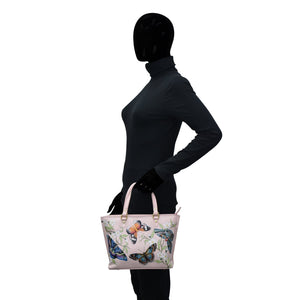 A mannequin wearing a black turtleneck and holding an Anuschka Medium Tote - 693 with hand painted butterfly prints on a white background.
