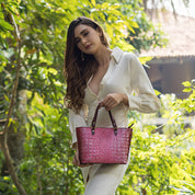 Woman posing with a pink, Anuschka Medium Tote - 693 in a garden setting.