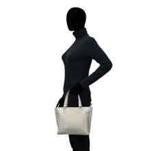 Load image into Gallery viewer, Mannequin wearing a black outfit holding a white Anuschka leather Medium Tote - 693 with a zippered pocket.
