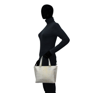 Mannequin wearing a black outfit holding a white Anuschka leather Medium Tote - 693 with a zippered pocket.