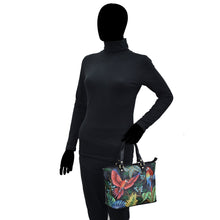 Load image into Gallery viewer, A mannequin dressed in a black turtleneck and pants, holding a hand-painted Anuschka Medium Tote - 693.
