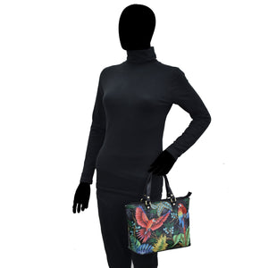 A mannequin dressed in a black turtleneck and pants, holding a hand-painted Anuschka Medium Tote - 693.