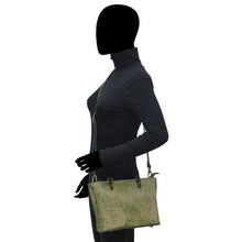 Load image into Gallery viewer, A side profile of a mannequin with a blacked-out face wearing a dark turtleneck and gloves, holding an Anuschka Medium Tote - 693.
