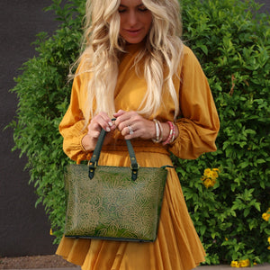 A woman in a yellow dress holding a green patterned Anuschka Medium Tote - 693.