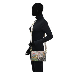 Mannequin displaying an Anuschka Triple Compartment Crossbody - 696 shoulder bag with a printed design, dressed in a black turtleneck and pants, perfect for organized traveling light.