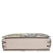 A cushioned bench with a floral design, beige base, and Anuschka 696 triple compartment crossbody for organized traveling light.