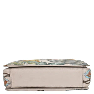 A cushioned bench with a floral design, beige base, and Anuschka 696 triple compartment crossbody for organized traveling light.