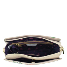 Load image into Gallery viewer, Cream-colored Anuschka Triple Compartment Crossbody handbag with purple interior and contents partially visible, perfect for traveling light.
