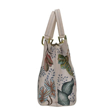 Load image into Gallery viewer, Side view of a chic, beige Anuschka Medium Satchel - 697 with a floral and leaf pattern.
