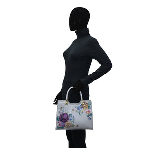 Side profile of a mannequin wearing a black bodysuit and holding an Anuschka Medium Satchel - 697 with a chic touch.