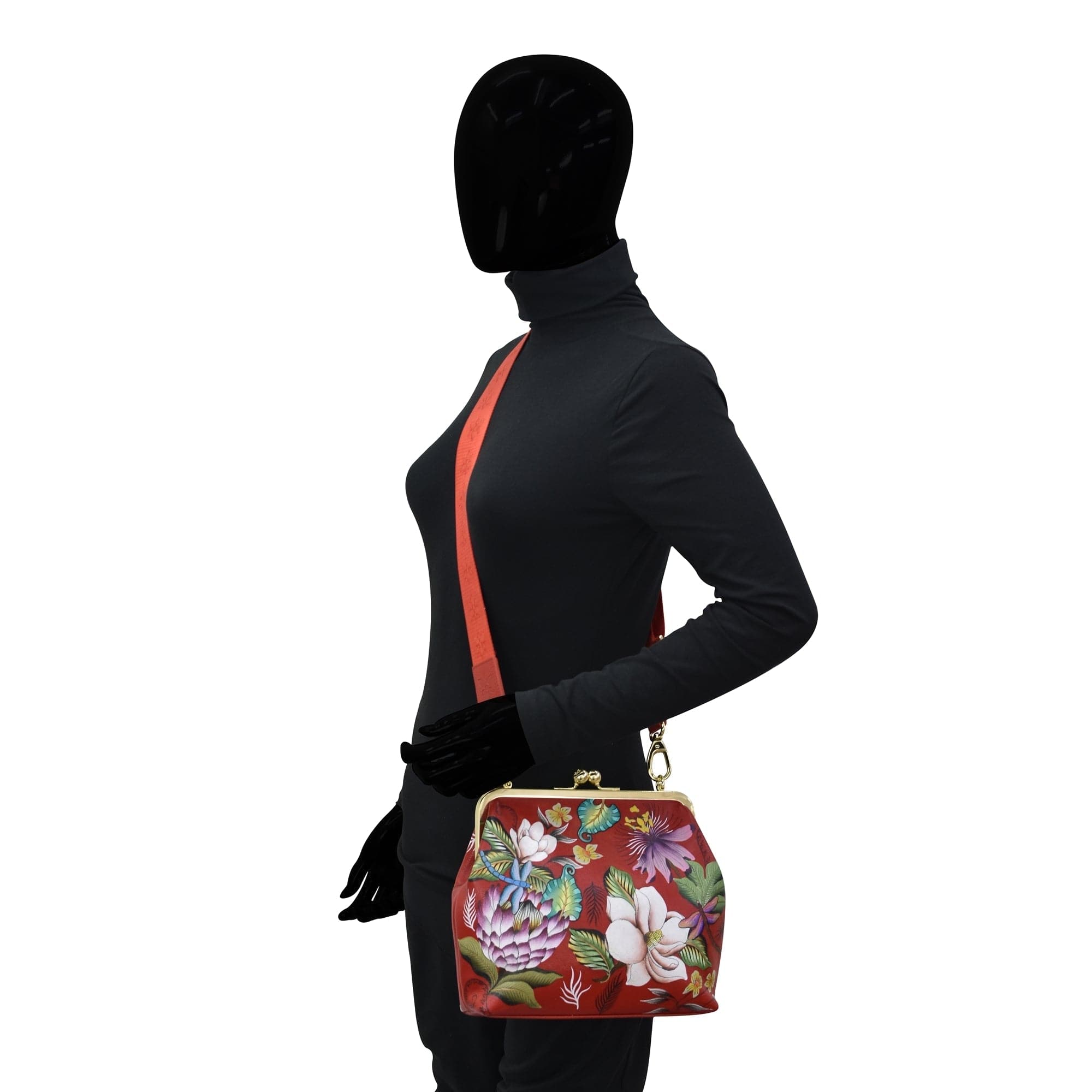 A mannequin with a black full-body suit and a featureless head holding an Anuschka Medium Frame Crossbody - 700.