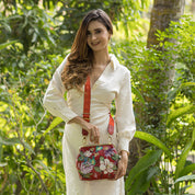 A woman in a white dress holding a red Anuschka Medium Frame Crossbody - 700.