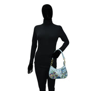 Mannequin wearing a black full-body suit and gloves, holding an Anuschka Small Convertible Hobo - 701 with a floral and butterfly design.