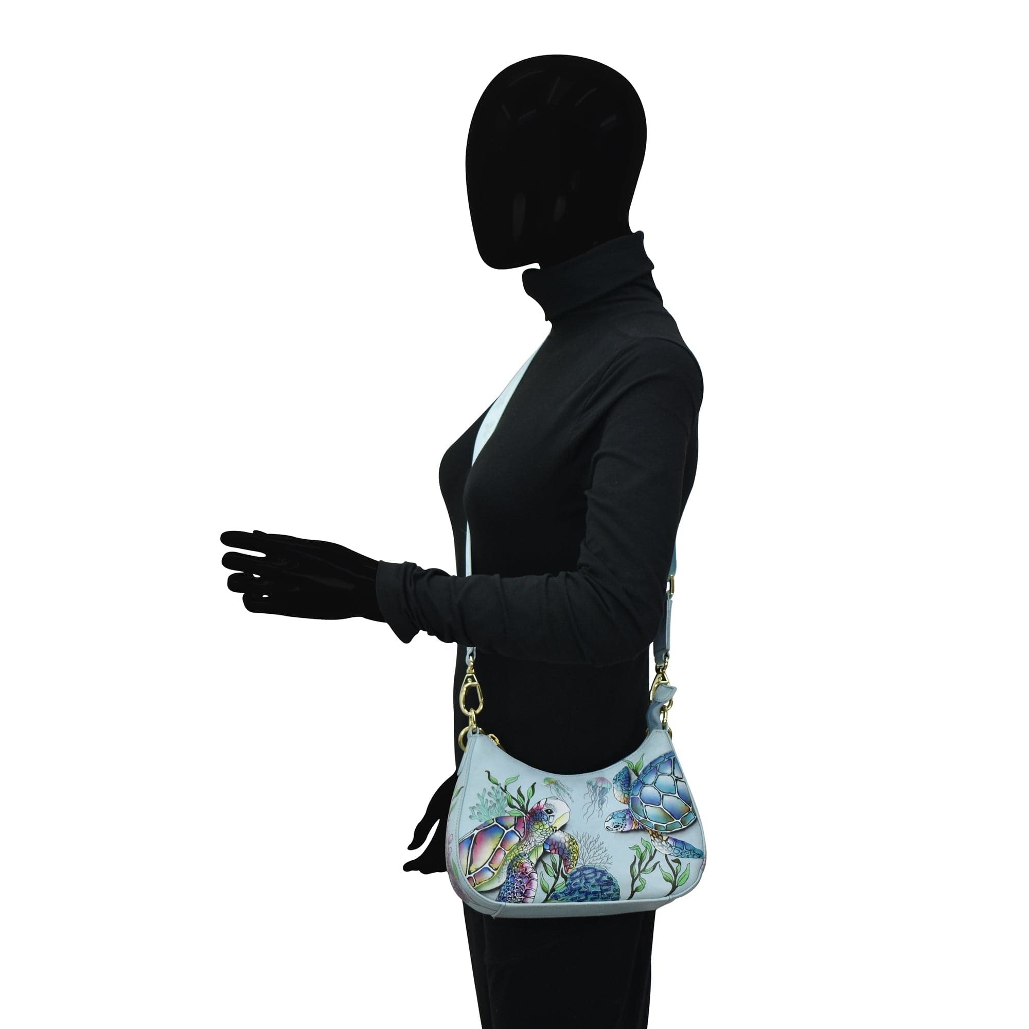 Mannequin with a black hoodie and gloves carrying an Anuschka Small Convertible Hobo - 701, isolated on a white background.