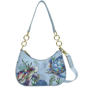 Light blue Anuschka Small Convertible Hobo - 701 with a colorful sea turtle and marine life design, featuring a gold chain strap and a white leather accent.