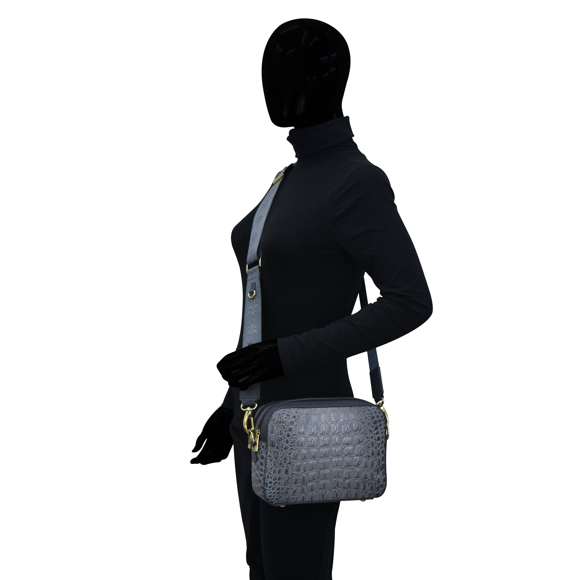 Mannequin wearing a black outfit and showcasing a grey Anuschka Twin Top Messenger - 704 with an adjustable strap.
