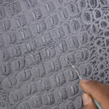 Load image into Gallery viewer, A person engraving a pattern onto the gray surface of a genuine leather Anuschka Organizer Wallet Crossbody - 1149 with a carving tool.
