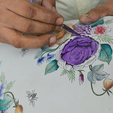 Load image into Gallery viewer, Close-up of a person&#39;s hands painting a stylish, detailed floral design with Anuschka&#39;s Medium Satchel - 697 watercolors.
