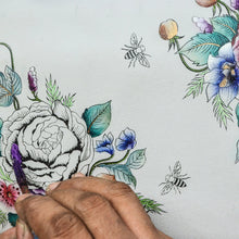 Load image into Gallery viewer, Hand painting a detailed floral design on a genuine leather Anuschka Round Coin Purse - 1175, featuring a large peony, smaller flowers, leaves, and bees.
