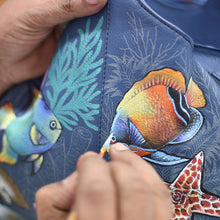 Load image into Gallery viewer, Hand stitching colorful fish designs onto an Anuschka Medium Tote - 693.
