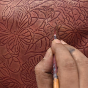 Hand painting detailed floral patterns on a Anuschka Leather Adjustable Leather Wrist Band - 1176.